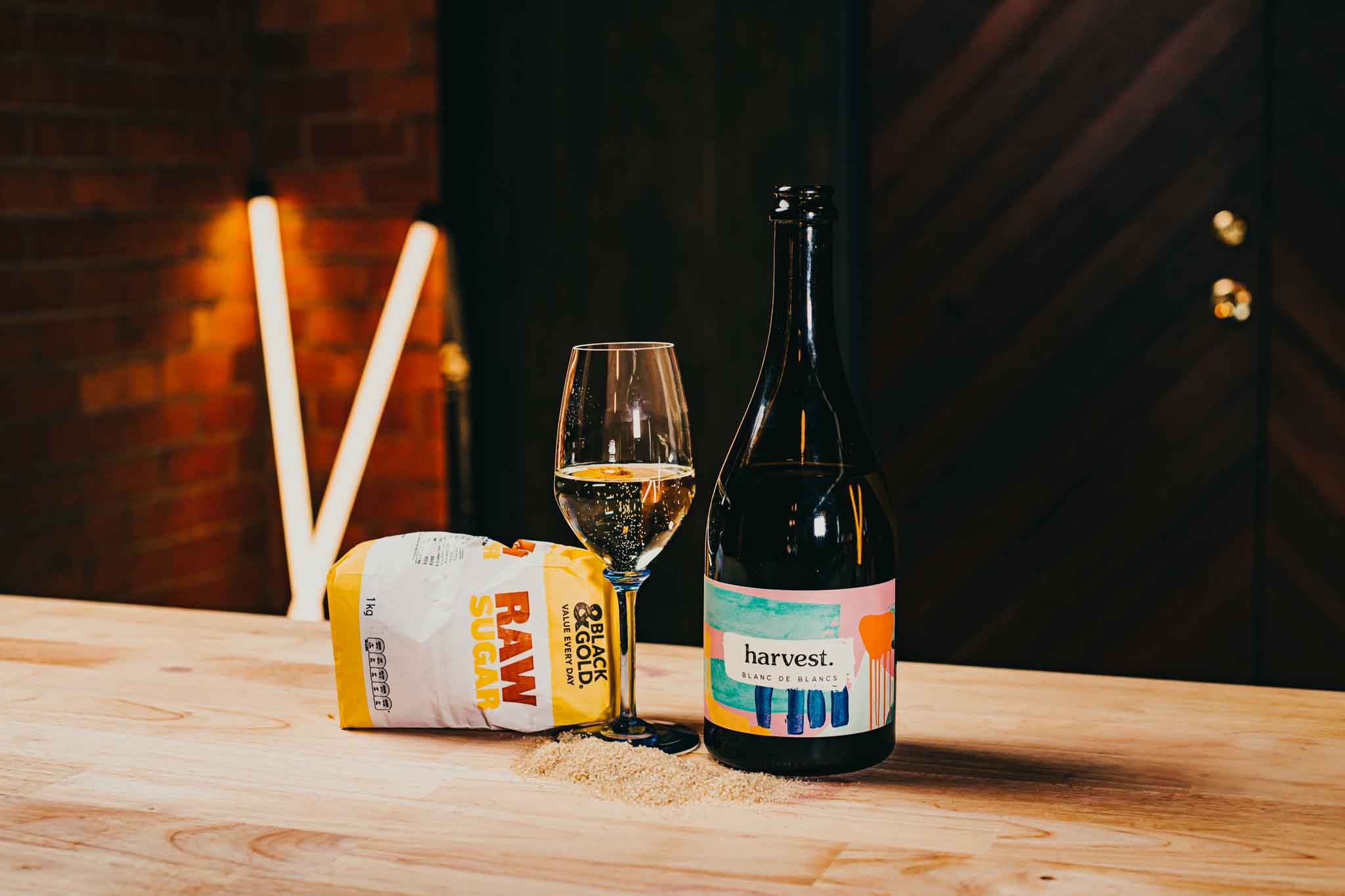 sugar and wine. a bottle sparkling wine and a bag of raw sugar